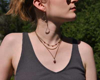 Dripping in Pearls necklace stack with earrings in blush with earrings on model in front of trees