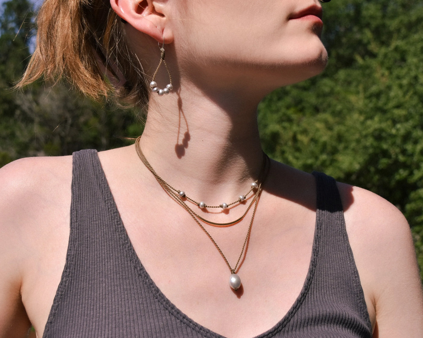 Dripping in Pearls necklace stack with earrings in silver on model with trees in background