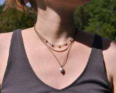 Dripping in Pearls necklace stack in silver on model with trees in background