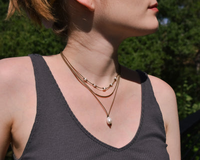 Dripping in Pearls necklace stack in white on model with trees in background