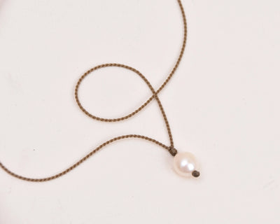 pearl drop necklace in white on white background