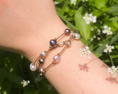 Tula Blue's Journey Bracelet in mixed pearl on model wrist in front of greenery closeup