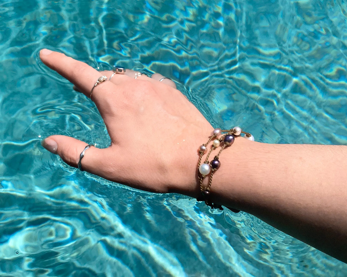 Tula Blue's Journey Bracelet in mixed pearl on model wrist in water closeup