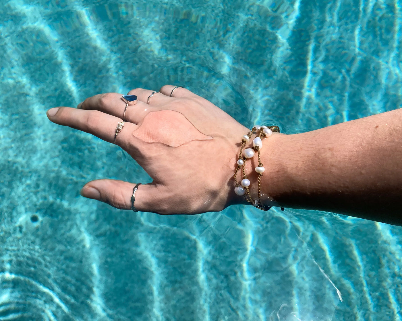 Tula Blue's Journey Bracelet in white pearl on model wrist in water
