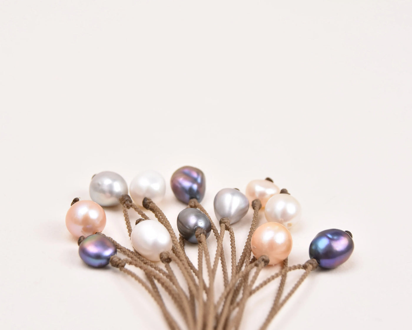 Pearl Drop Necklace in White, Peach, Peacock and Silver clumped on a white background