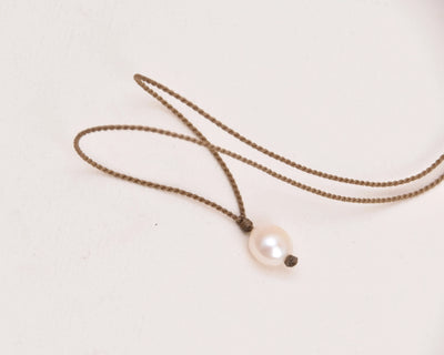 Pearl Drop Necklace in peach laying on a white background