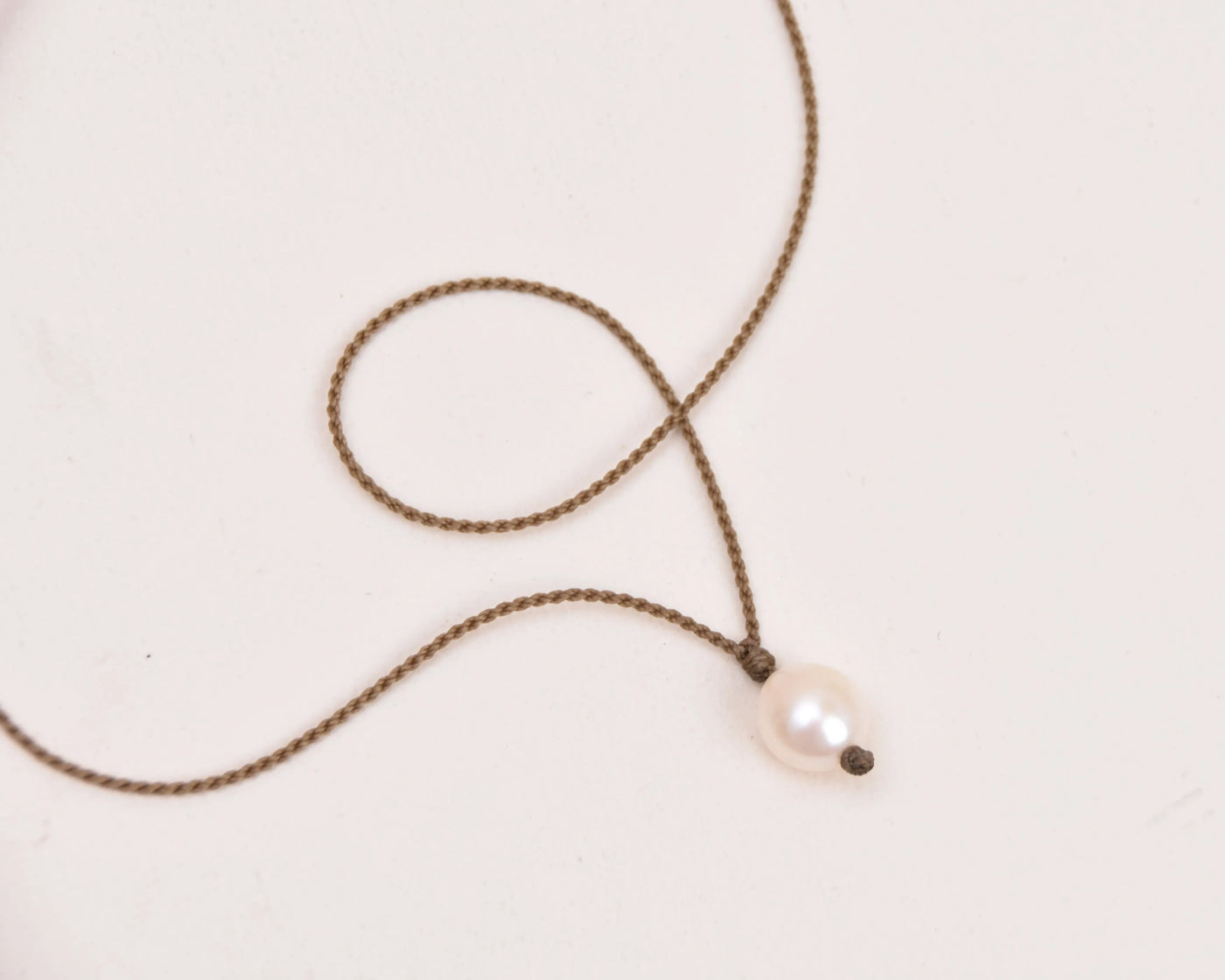 Pearl Drop Necklace in white laying on white background