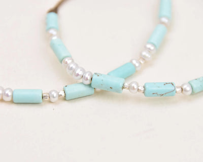 Turquoise, Pearl and Sterling Silver anklet and bracelet crossed on top of each other extreme closeup showing the pattern and variation of the turquoise 