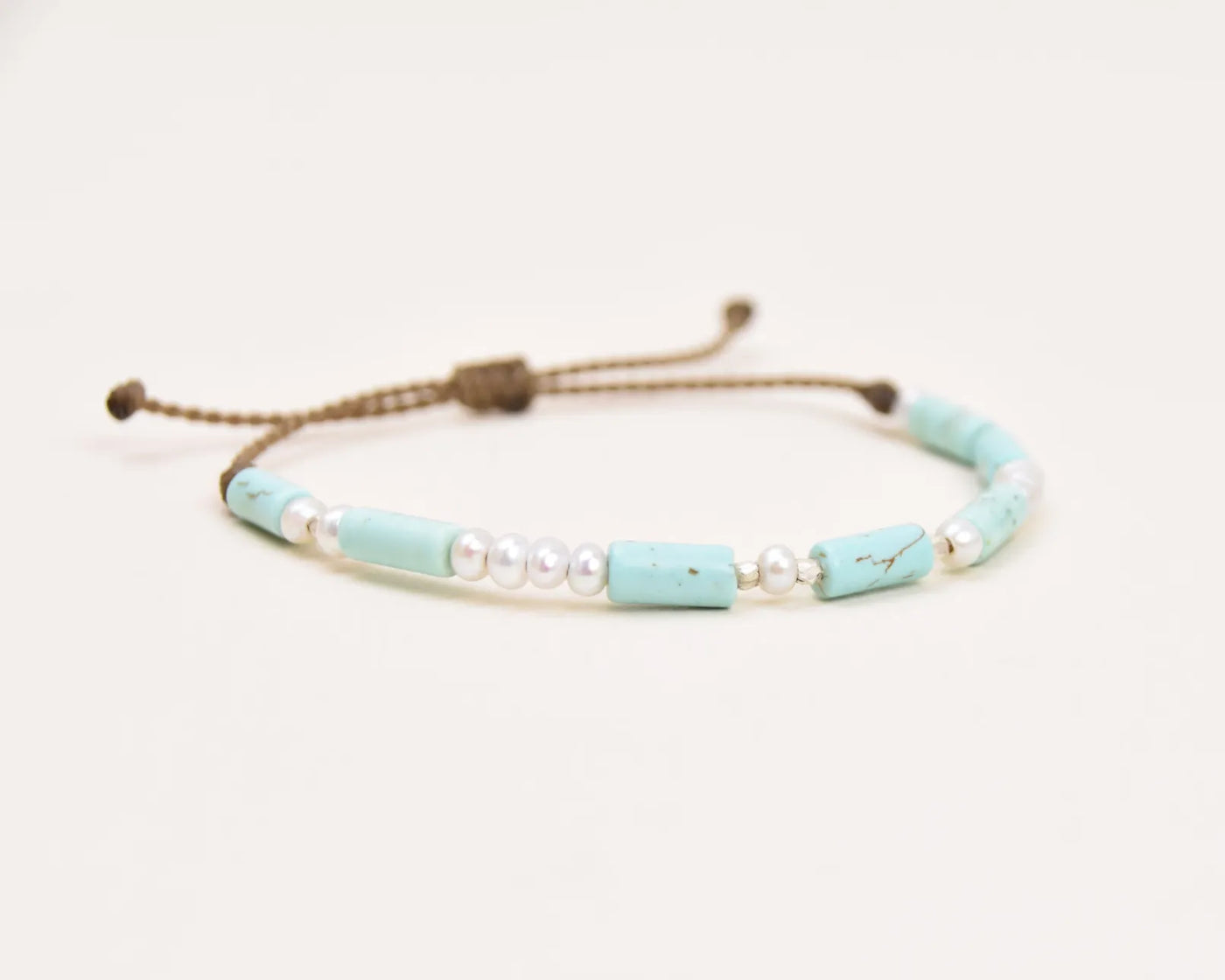 Turquoise, Pearl and Sterling Silver bracelet on white background viewed at an angle