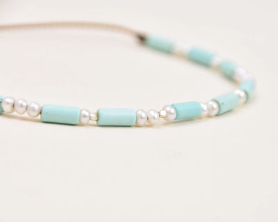 Turquoise, Pearl and Sterling Silver anklet layout on white background viewed at an extreme closeup 