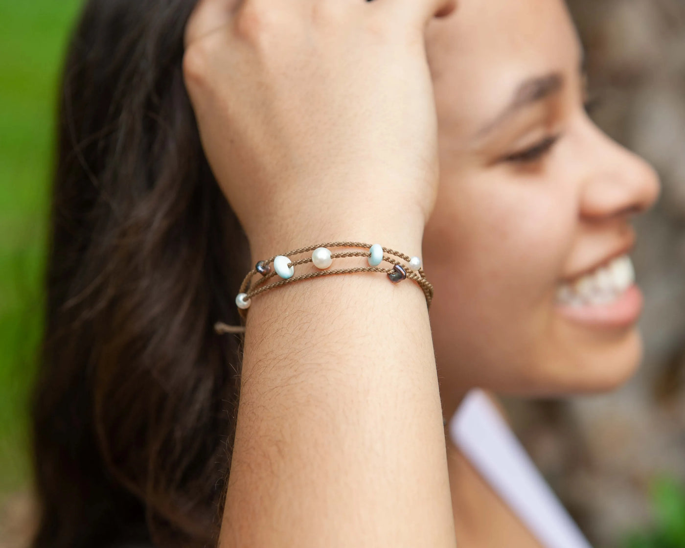 Seven Seas X PADI Riptide Bracelet with white pearl on model wrist with her smiling in the background